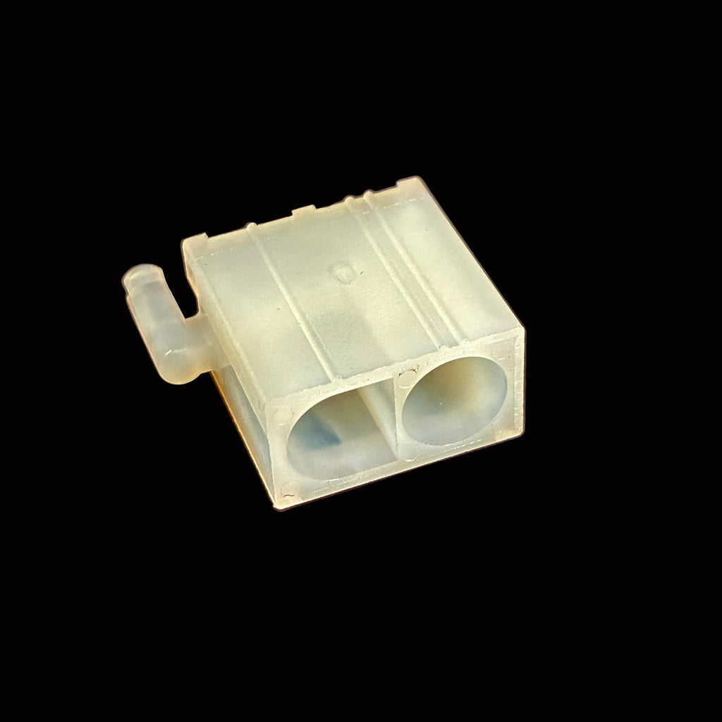 A small translucent plastic component with two circular openings and a short side tab, photographed on a black surface.