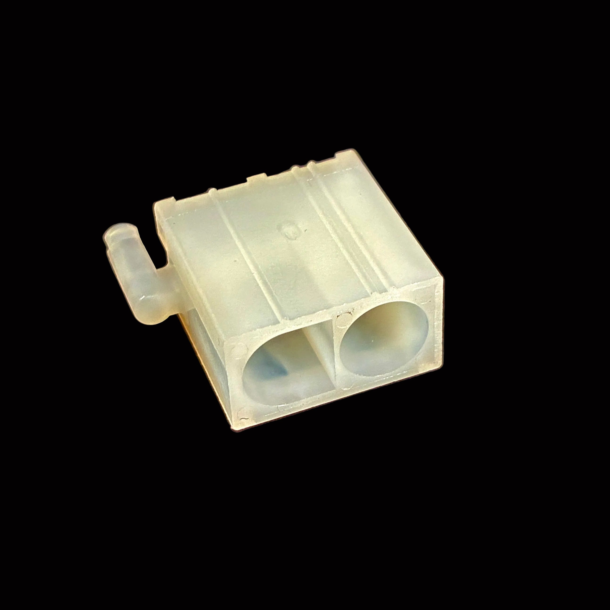 A small translucent plastic component with two circular openings and a short side tab, photographed on a black surface.